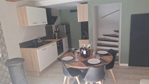 A dining area with a round table, black chairs, and a kitchen in the background.