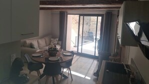 A dining area with a table set for four, a sofa, and a sliding glass door leading to an outdoor patio.