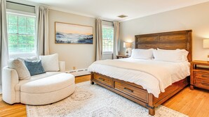A bedroom with a large bed, a sofa, a nightstand, and a painting on the wall. - Serene Hudson Valley Escape w/ Pool & Grill (Carmel Hamlet)