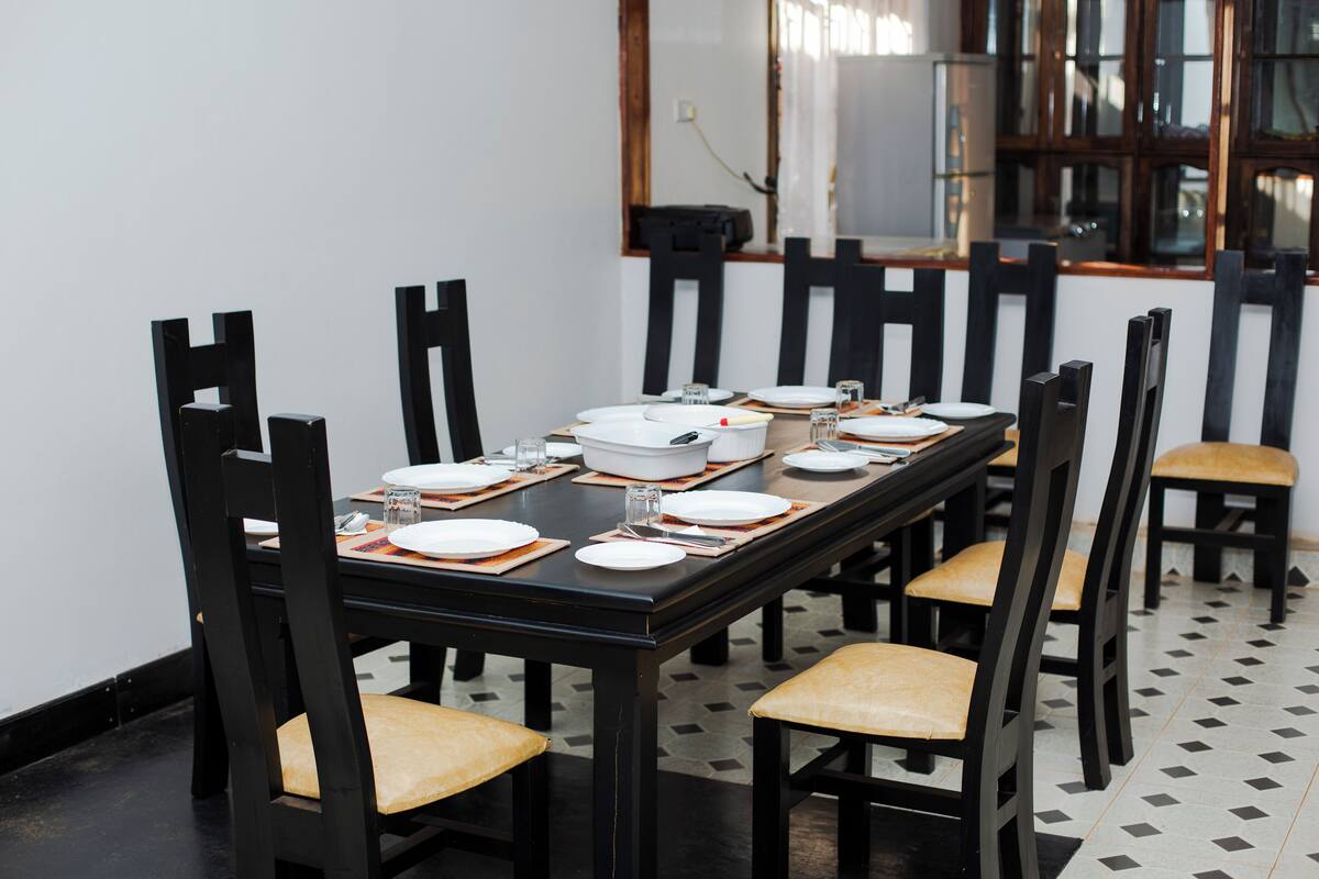 Una mesa de comedor dispuesta con platos, tazones y cubiertos, rodeada de sillas con asientos acolchados.