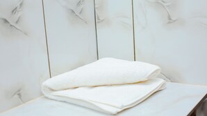 A white towel folded on a white marble-topped table against a white wooden wall. - Kili Share Hotel & Hotel (Himo)