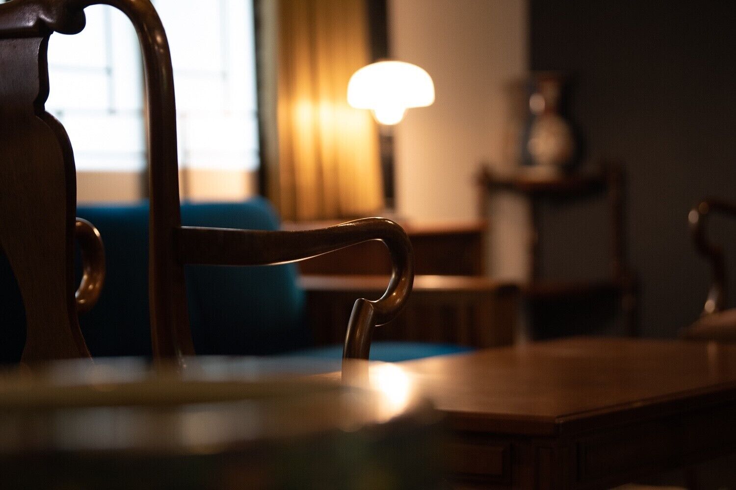 A wooden dining table with chairs, a lamp, and a sofa in the background.