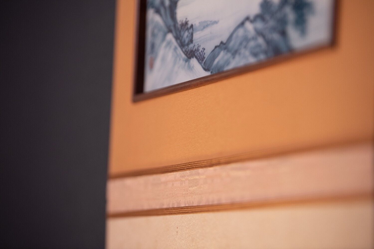 Primer plano de una pared con un cuadro que muestra un paisaje montañoso.