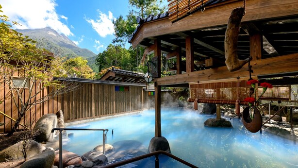 A traditional wooden bathhouse with a hot spring, surrounded by rocks and trees. - Taisho Yufunohana (Yufu)