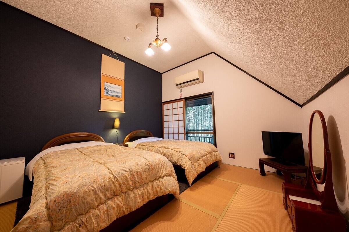 Ein Schlafzimmer mit zwei Betten, einem Fernseher und einer traditionellen japanischen Schiebetür.