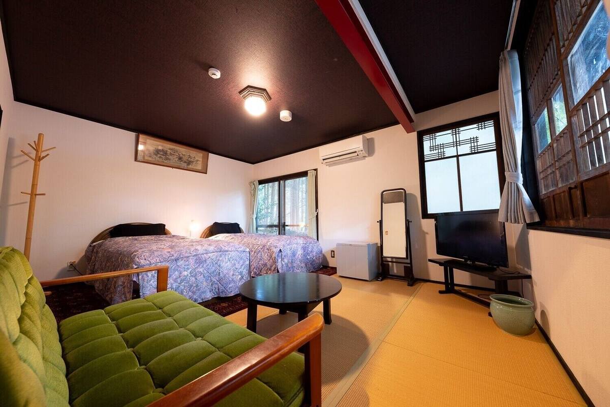 Ein Zimmer mit zwei Betten, einem Fernseher, einem Spiegel und einer Schlafcouch.