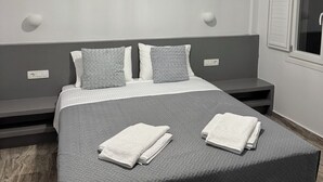 A modern bedroom with a large bed, grey bedding, and a unique pendant light. - Διαμέρισμα 1 Υπνοδωματίου (Καμάρι)