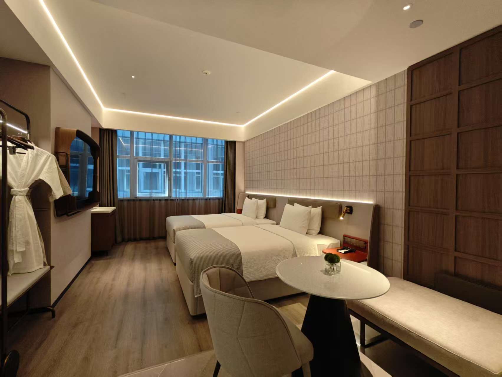 A modern hotel room with a large bed, a small round table, and a seating area.