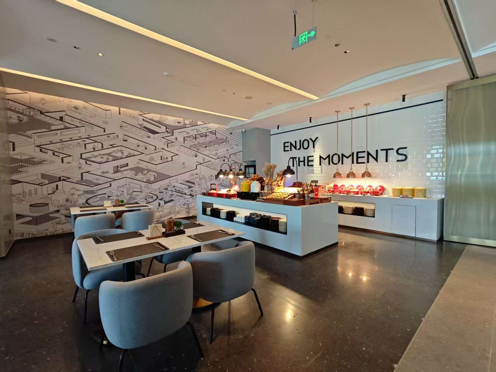 A modern interior with a dining area, a counter with food items, and a wall with a motivational quote.