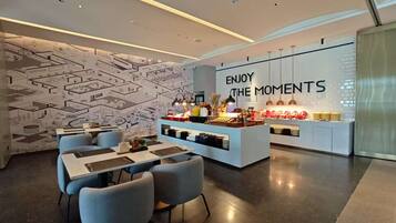 A modern interior with a dining area, a counter with food items, and a wall with a motivational quote.