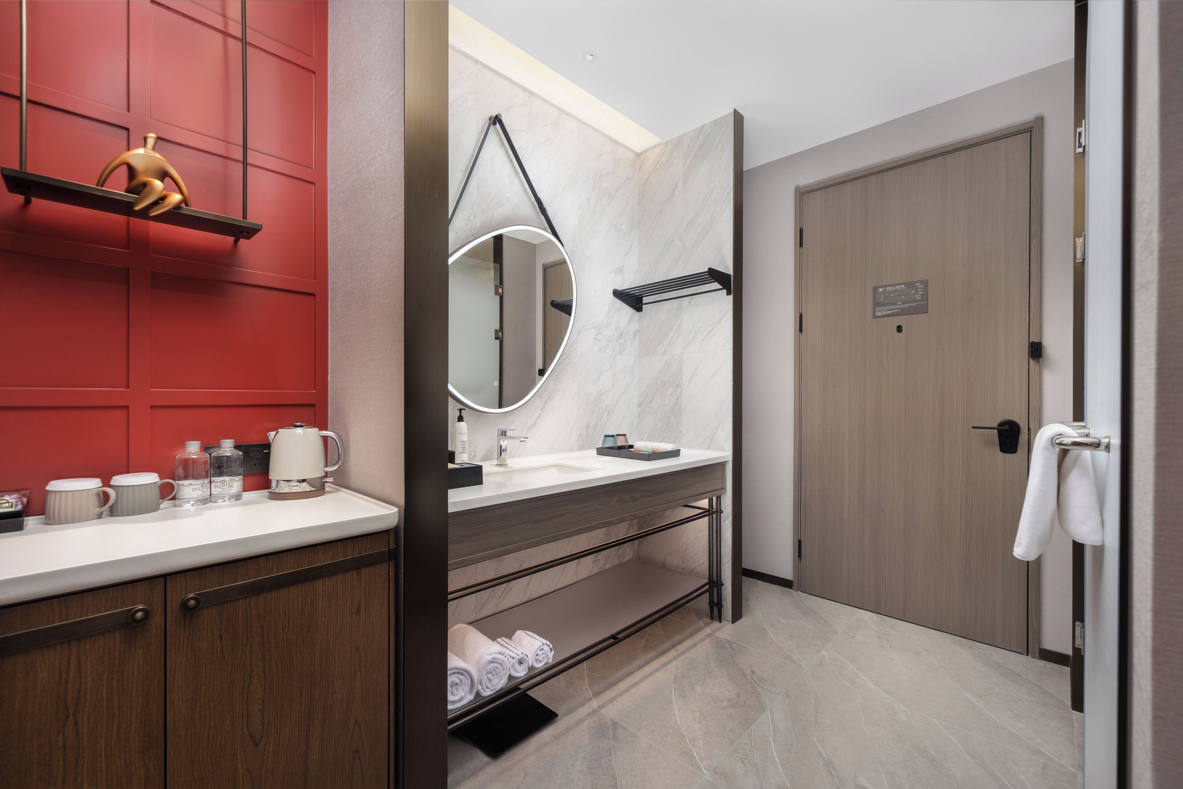 A modern bathroom with a white sink, a mirror, a towel rack, and a shelf with toiletries.