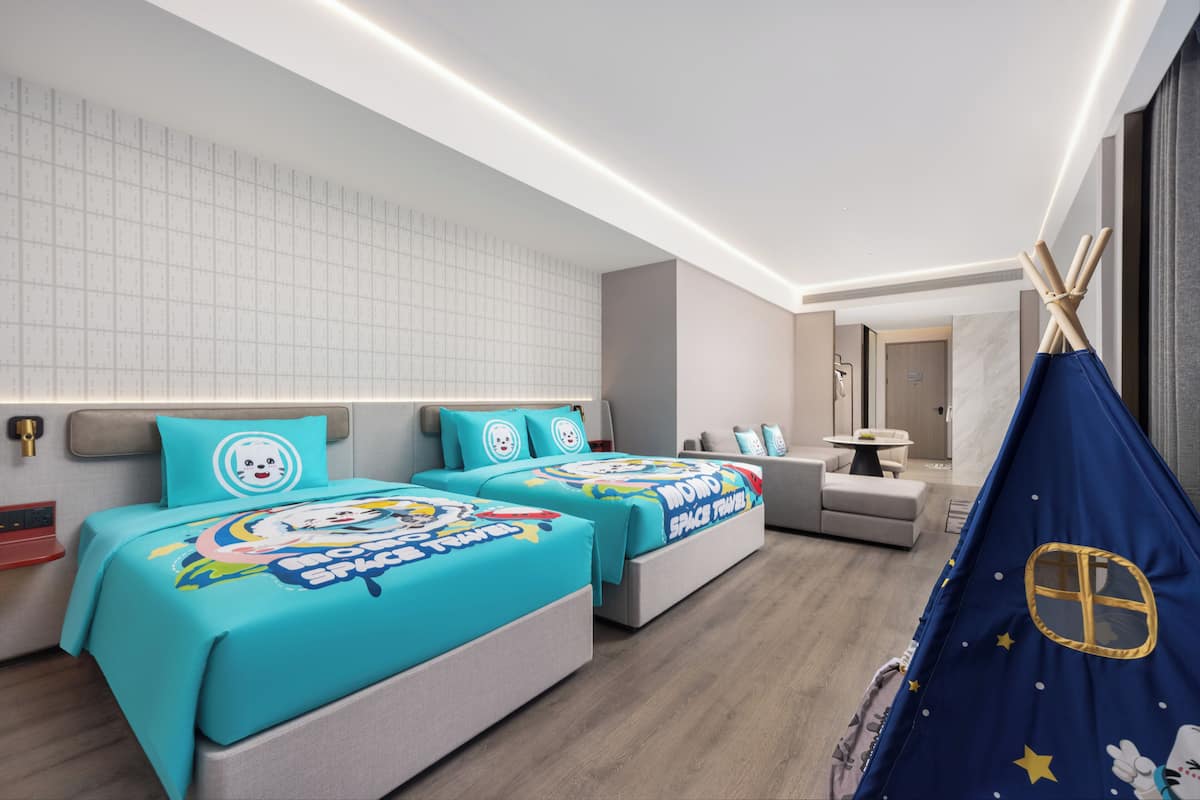 Une chambre d’hôtel moderne avec deux lits, un petit coin salon et une structure ressemblant à une tente.
