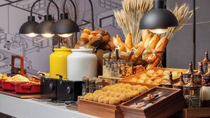 Ein Buffet mit verschiedenen Backwaren, darunter Brot und Gebäck, sowie eine Kaffeestation mit Espressomaschinen.
