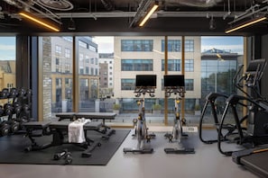 A gym with exercise equipment, a bench, and dumbbells. - Moxy Dublin Docklands (Dublin)