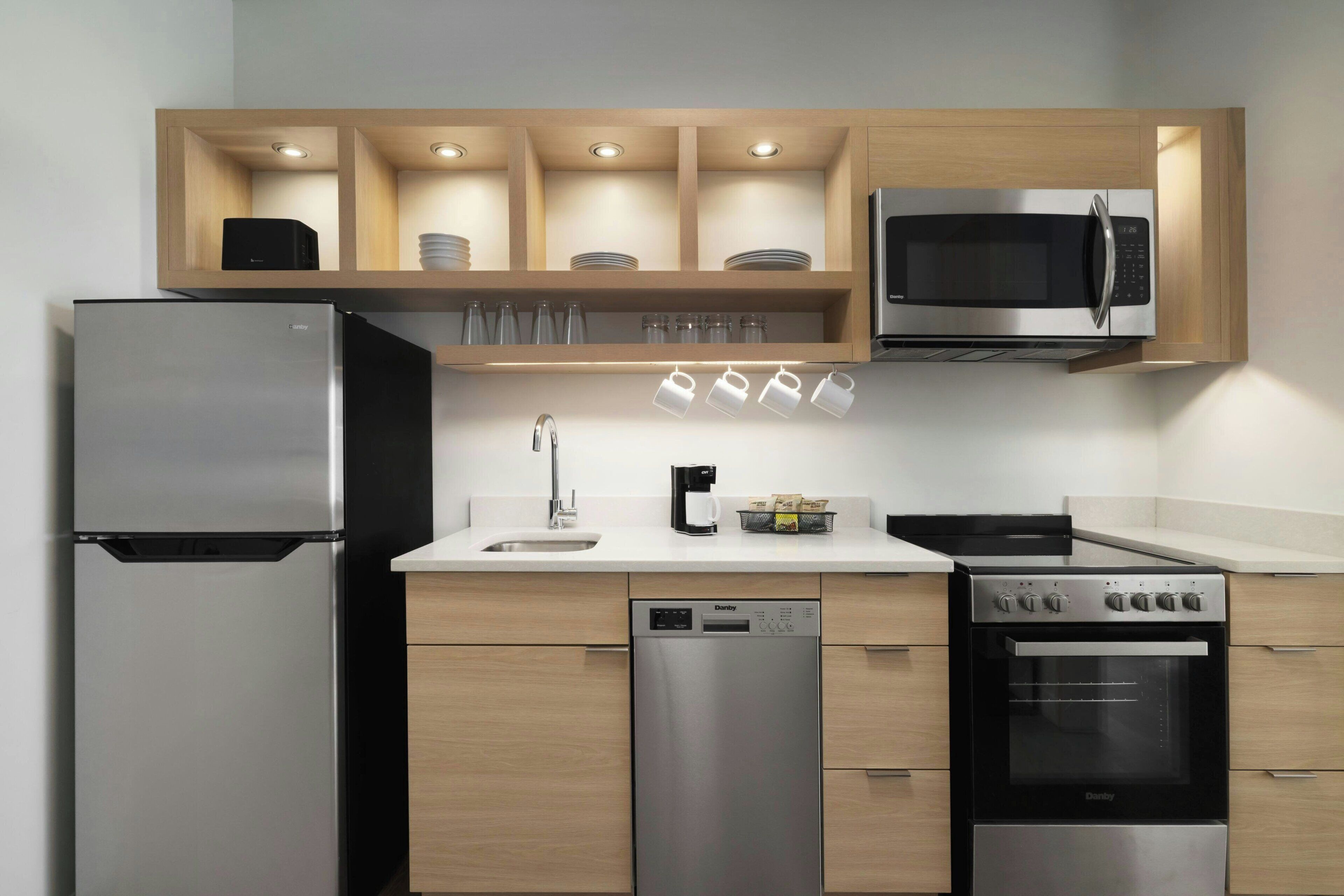 A modern kitchen with a refrigerator, microwave, dishwasher, stove, and cabinets.
