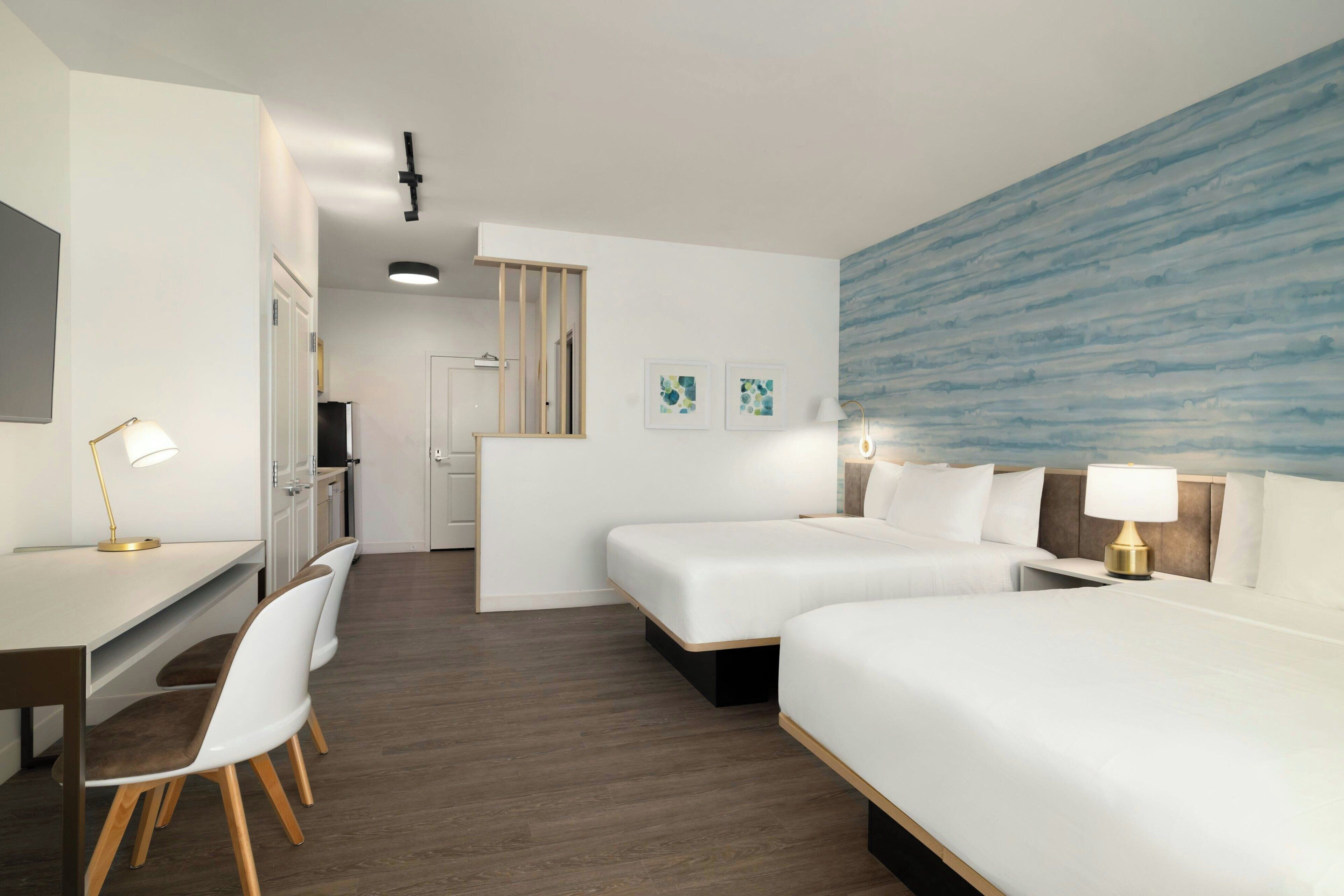Ein Hotelzimmer mit zwei Betten, einem Schreibtisch, einem Stuhl und einem großen Fenster mit Blick.