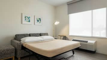 Un dormitorio con una cama, dos sillones, una lámpara de pie y una ventana con vistas.