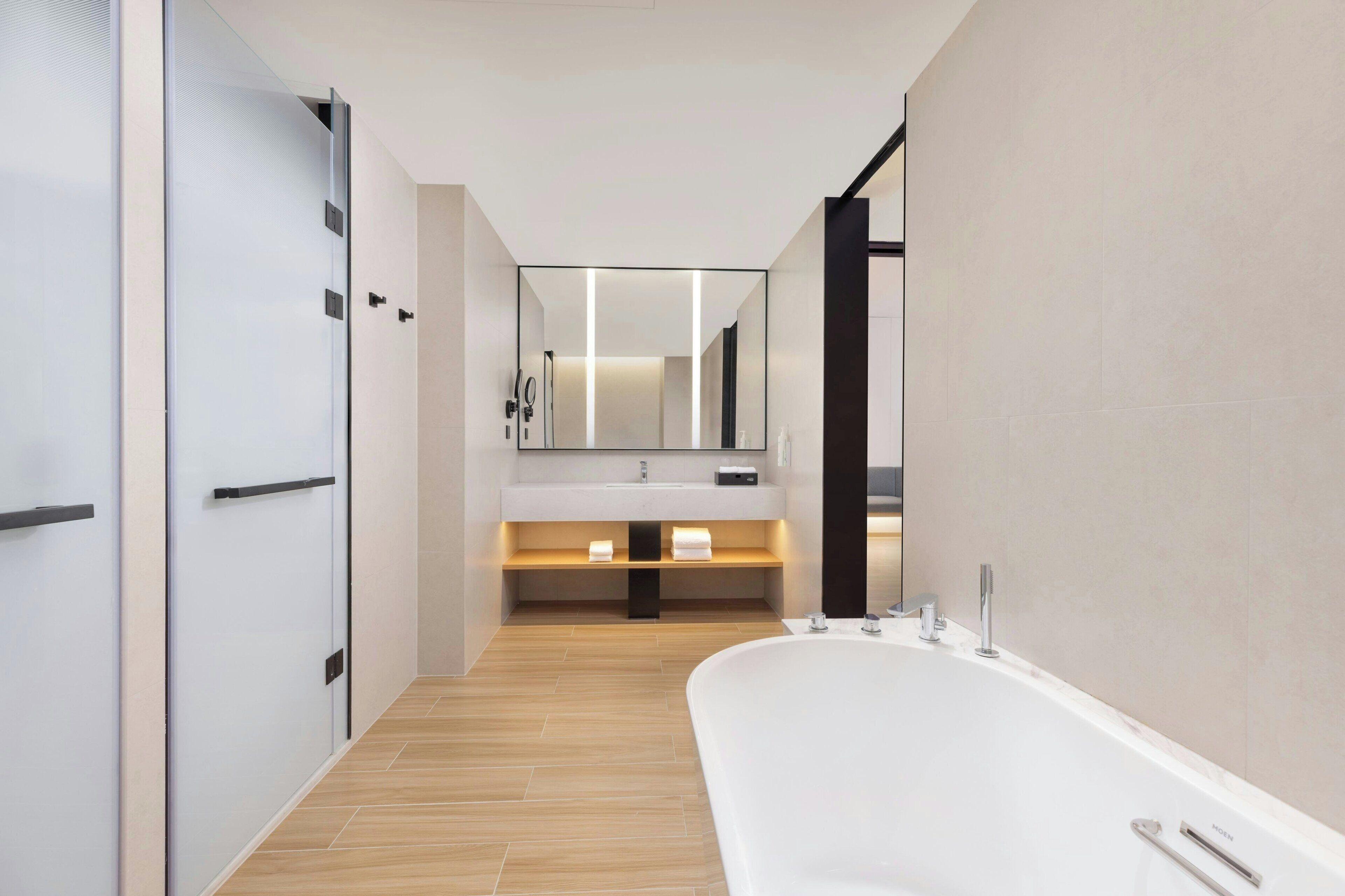 Een moderne badkamer met een vrijstaand bad, een wastafel met spiegel en een handdoekrek.