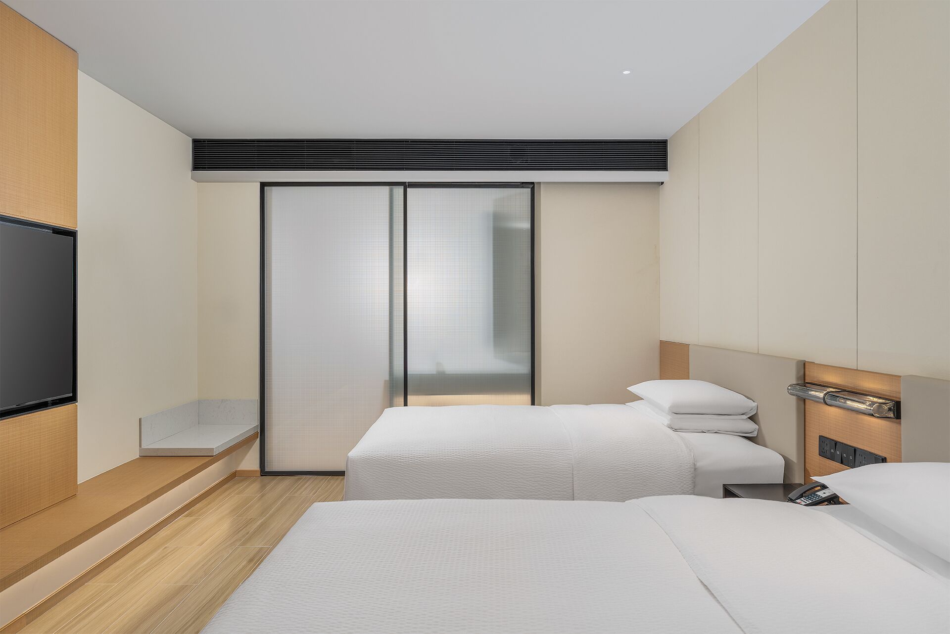 A modern hotel room with two beds, a TV, a sliding door closet, and a wooden floor.