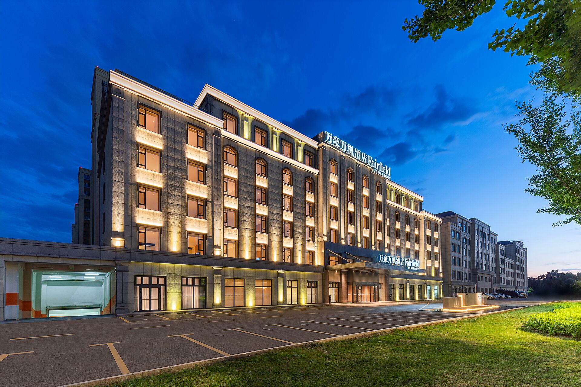 A multi-story hotel with a modern facade, large windows, and a well-lit entrance.