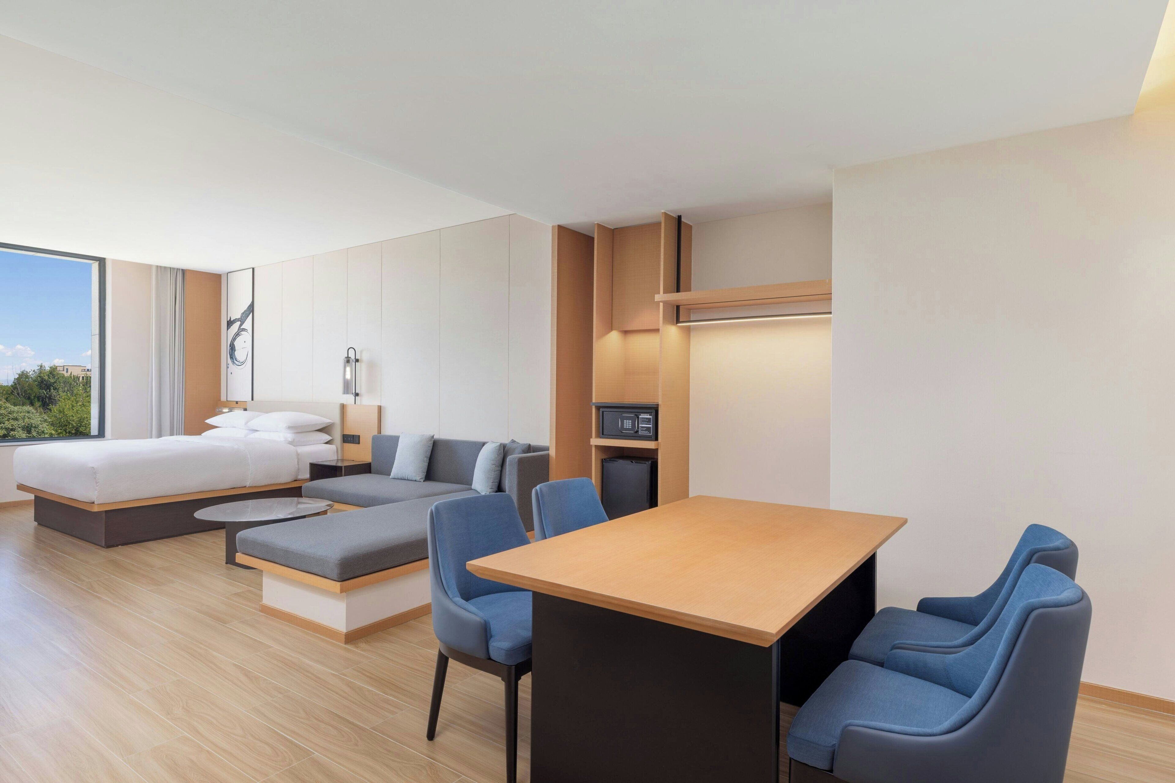 Una habitación de hotel moderna con cama, sofá, mesa de comedor y sillas.