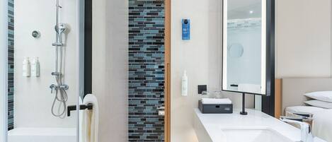 A modern bathroom with a shower, a sink, and a mirror.