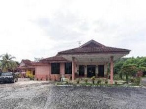 A single-story building with a pitched roof, a covered porch, and a gravel driveway.
