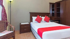 A hotel room with a bed, a nightstand, a wooden wardrobe, and a chair. - INB Resort Ayer Keroh Melaka (Malacca City)