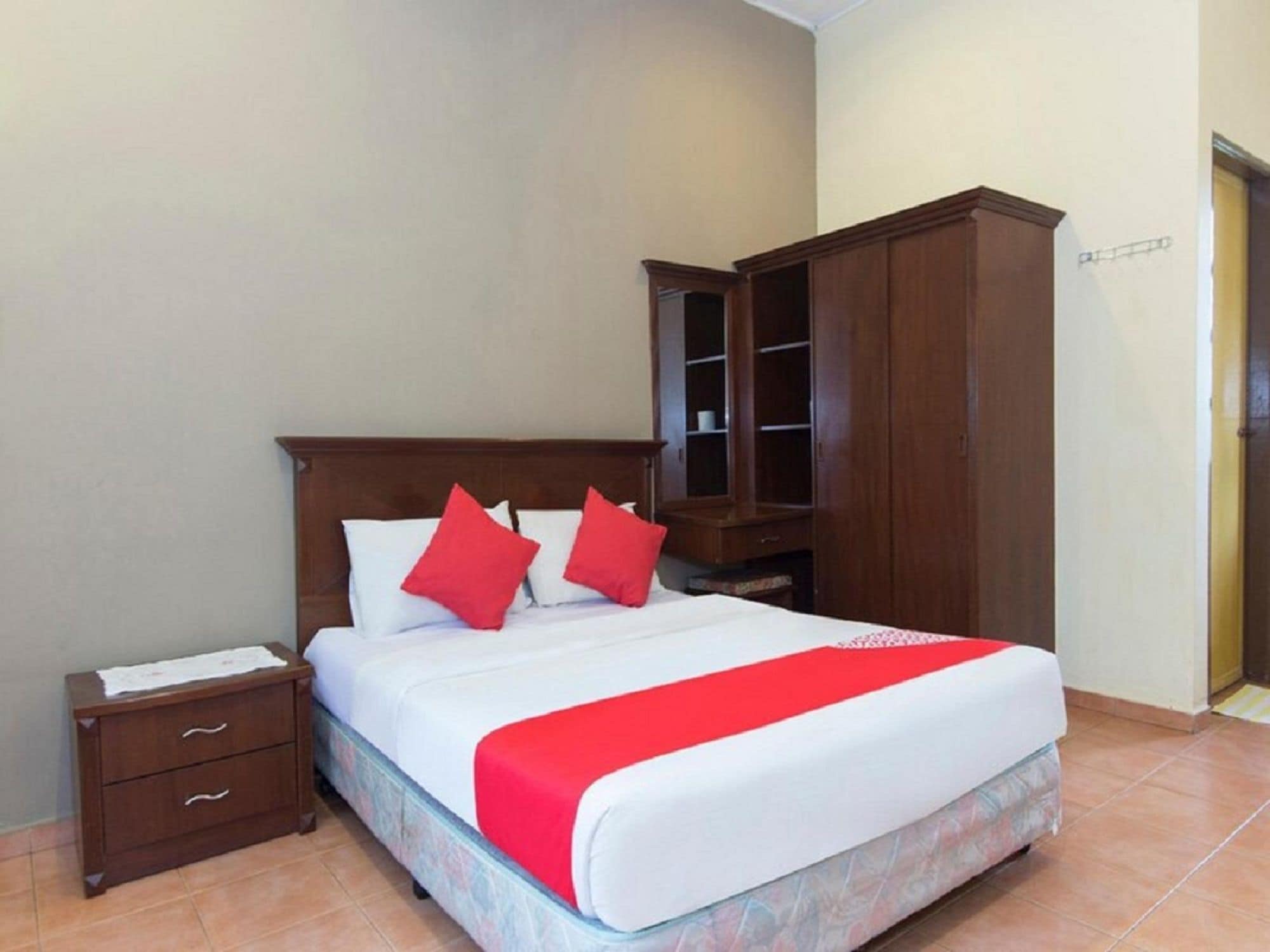 Une chambre d’hôtel avec un lit, une table de chevet, une armoire et une porte.