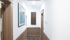 A hallway with a framed abstract painting, a wooden panel wall, and a patterned rug.