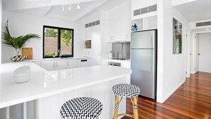 Une cuisine moderne avec des meubles blancs, un grand îlot central et un réfrigérateur en acier inoxydable.