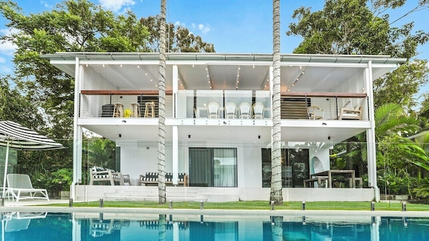 Une maison à deux étages avec une piscine à l’avant.