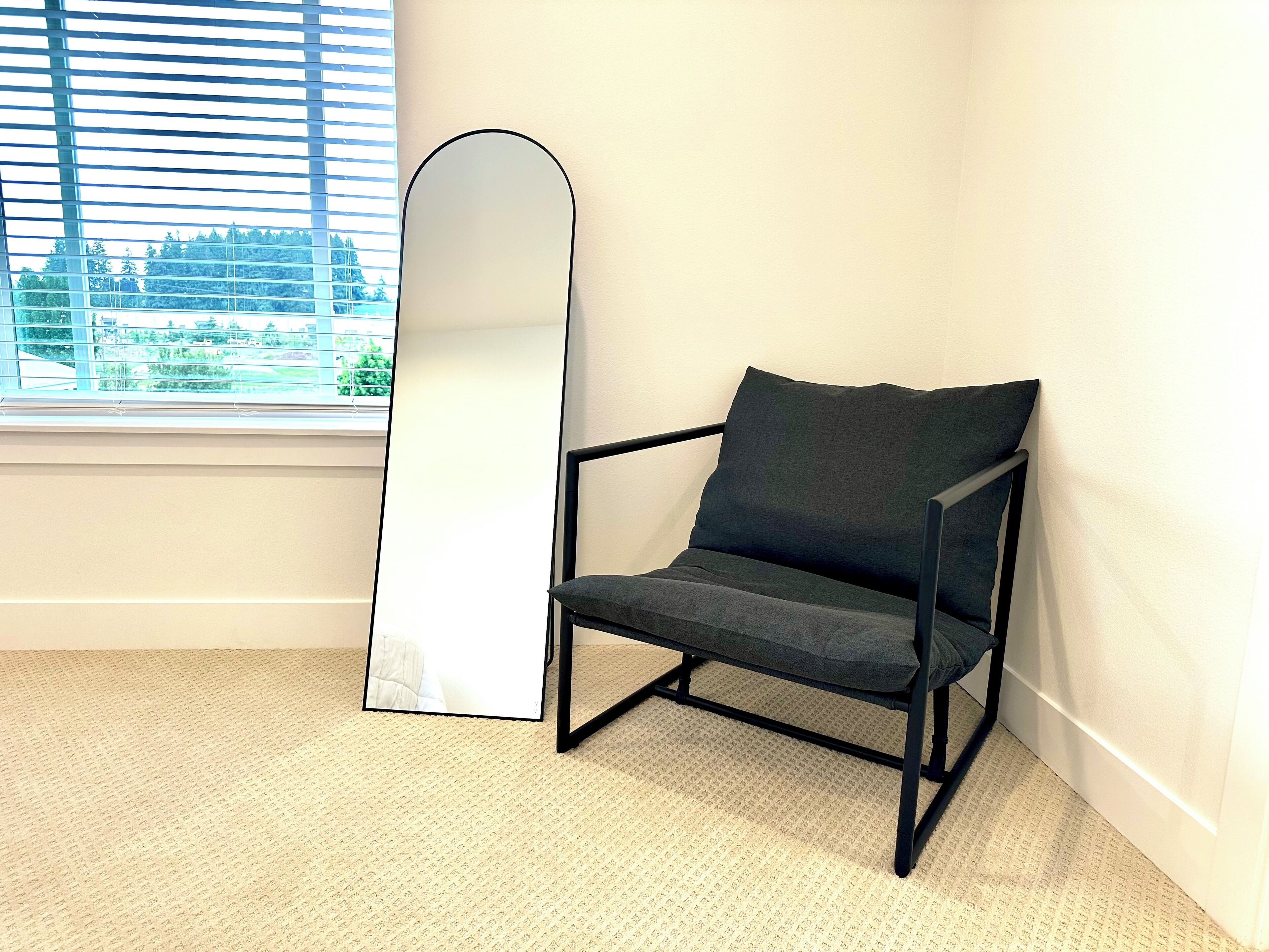 Une pièce avec un grand miroir, une chaise et une fenêtre donnant sur la ville.