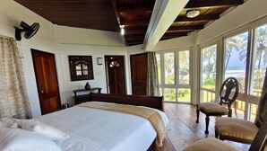Un dormitorio con una cama grande, muebles de madera y vistas al exterior a través de amplios ventanales.