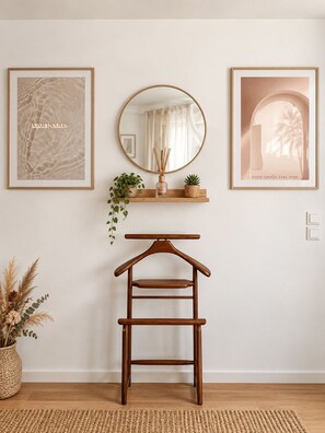 A minimalist room with a wooden hanger, framed artwork, a mirror, and a small shelf with plants and a bottle. - Villa Les Chênes Verts – Private Pool – Hot Tub – Provence – Sleeps 10 (Sainte-Anastasie-sur-Issole)