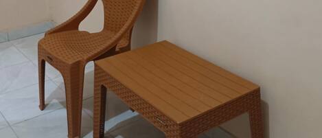 A room with a plastic chair and a wooden bench against a plain wall.