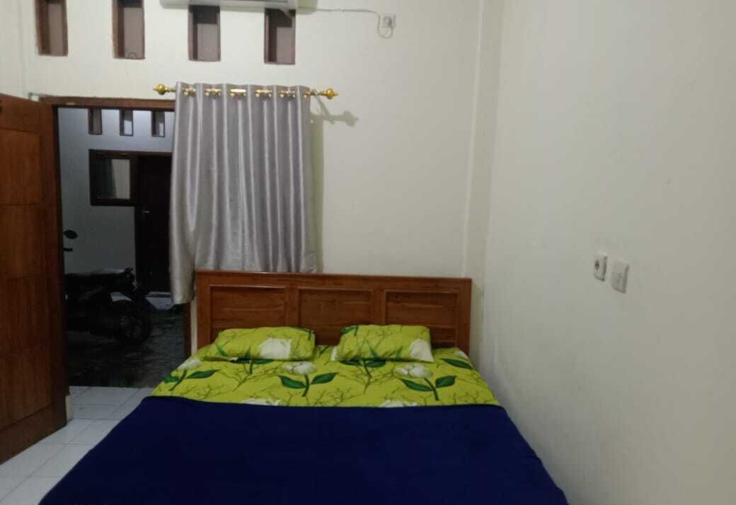 Un dormitorio con cama, cabecero de madera y ventana con cortinas.