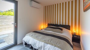 Un dormitorio moderno con una cama grande, un ventanal corredero al exterior y un aire acondicionado de pared.