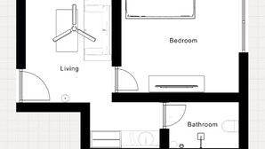 Een slaapkamer met een bed, een woonkamer met een televisie en een stoel, en een badkamer met toilet en wastafel.