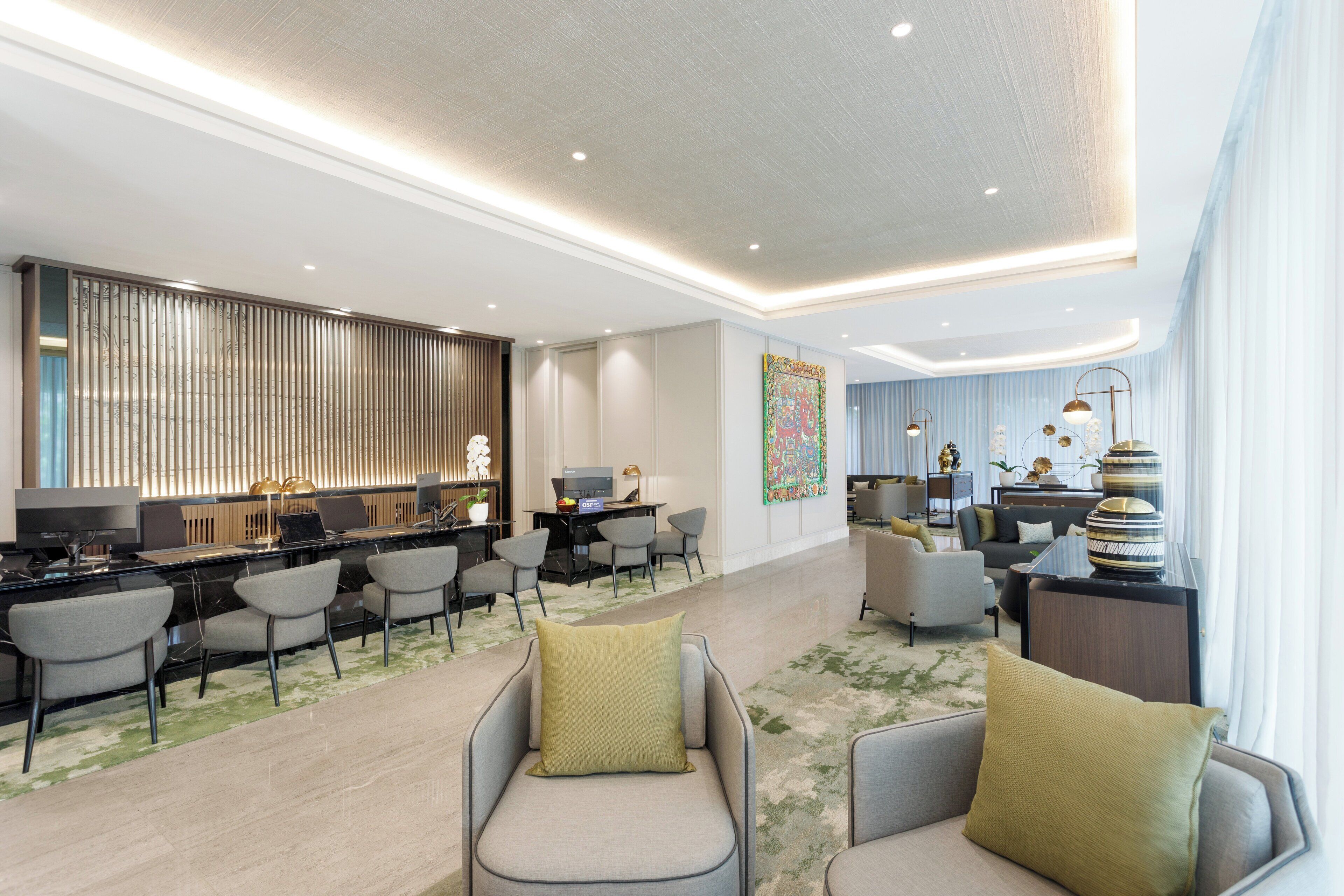 Un hall d’hôtel moderne comprenant un comptoir d’accueil, un espace salon et un espace repas.