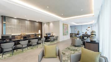 Un hall d’hôtel moderne comprenant un comptoir d’accueil, un espace salon et un espace repas.