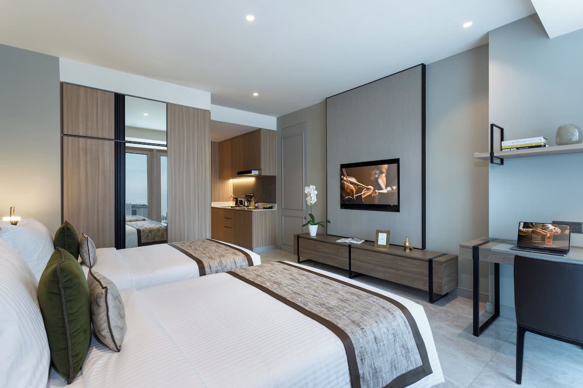 Une chambre d’hôtel moderne équipée de deux lits, d’une télévision, d’un bureau et d’une kitchenette.
