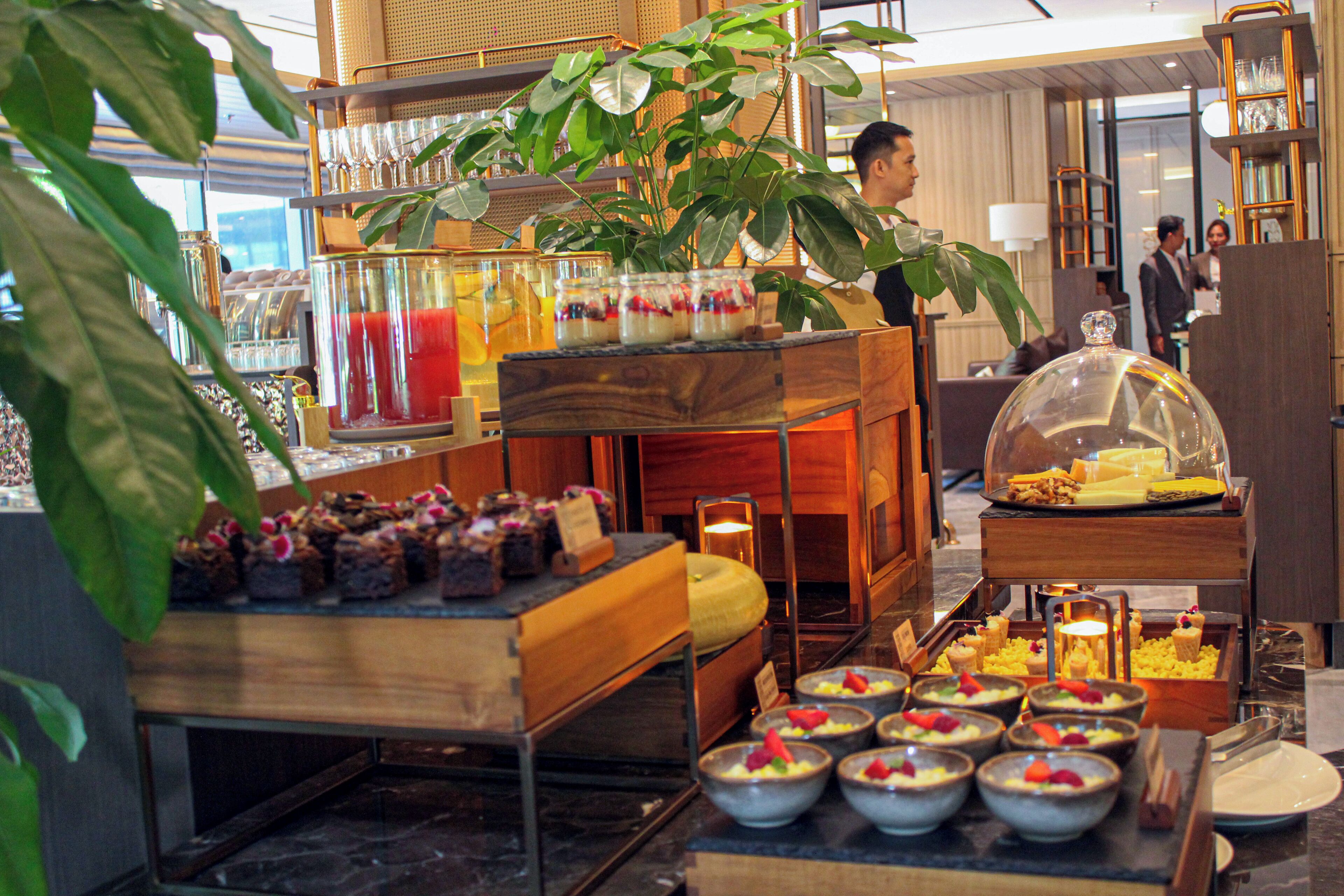 A buffet setup with various food items and a decorative plant.