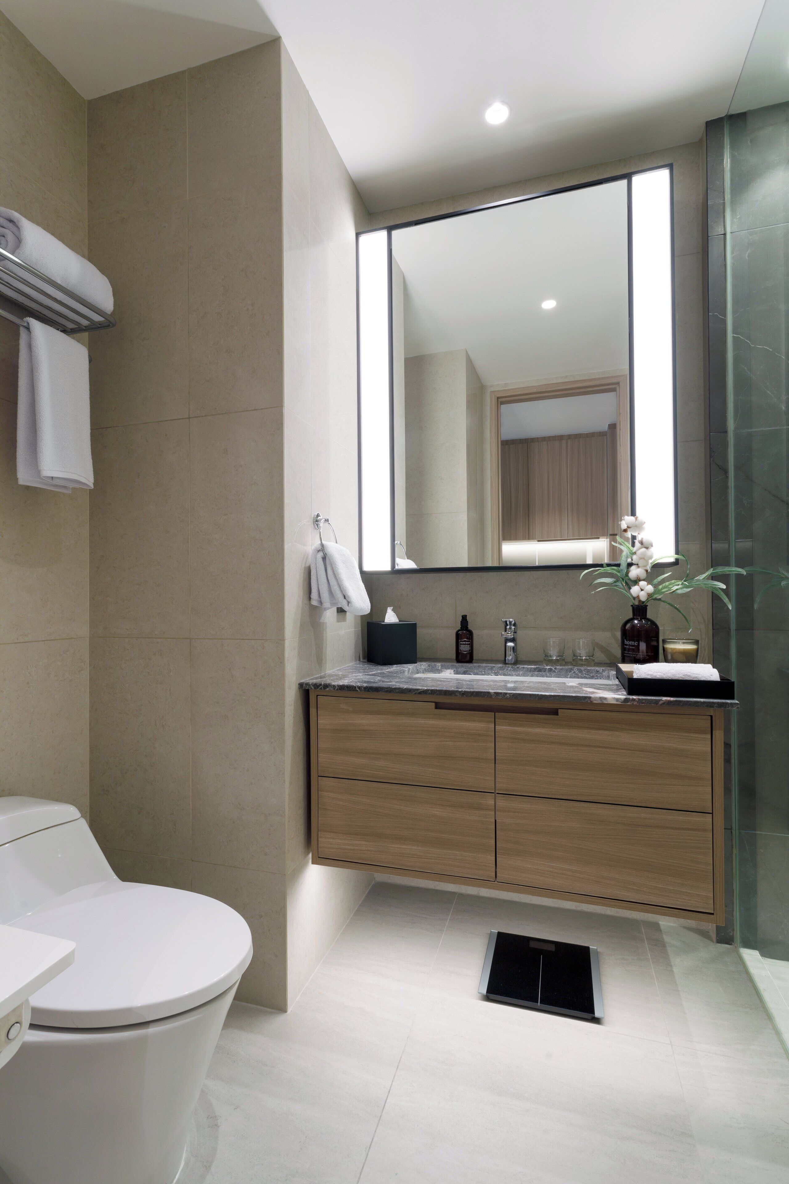 A modern bathroom with a toilet, sink, and mirror.
