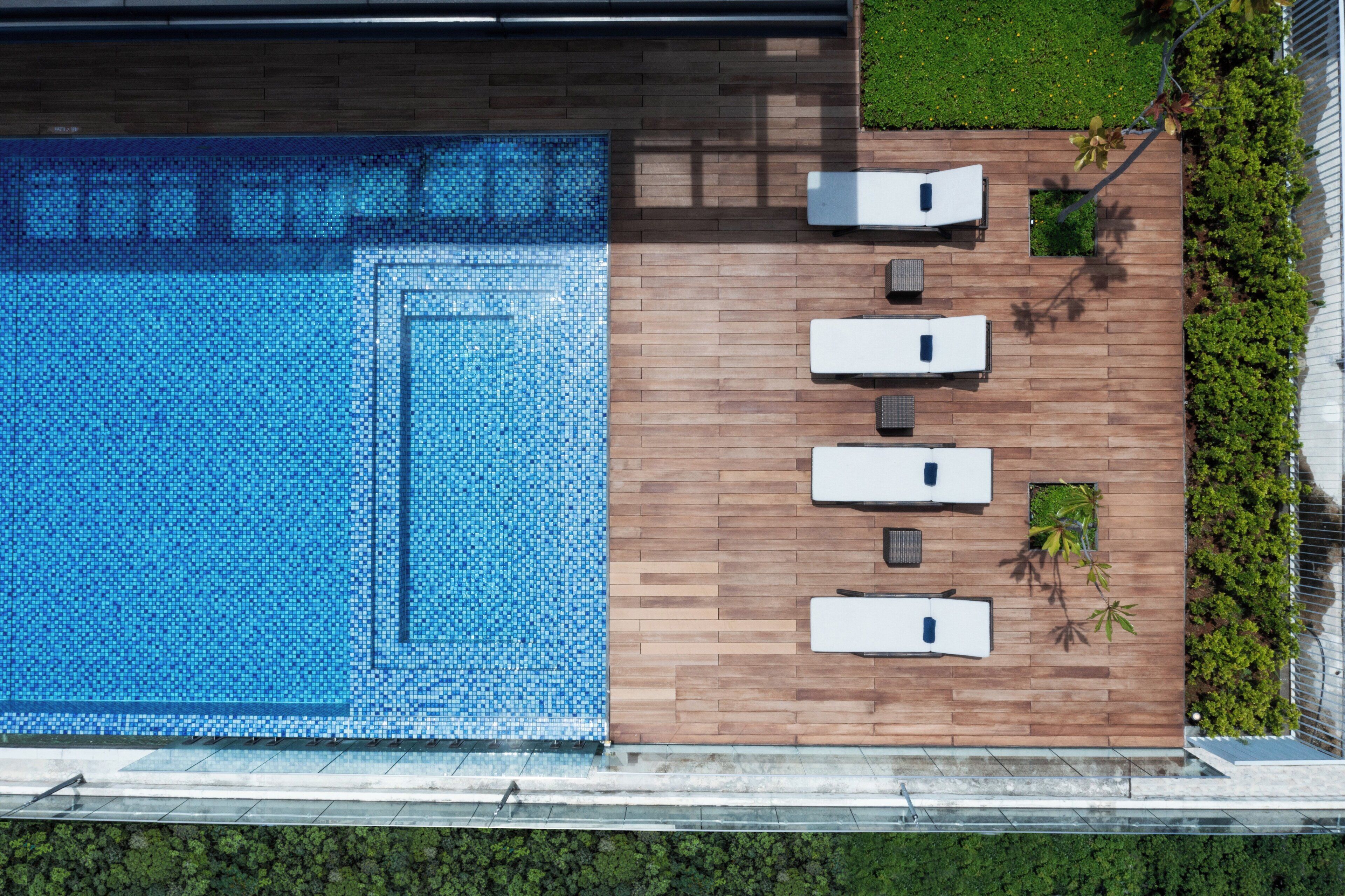 A rooftop pool with a wooden deck and lounge chairs.