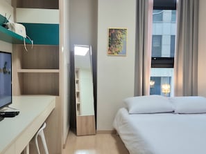A hotel room with a bed, a desk with a computer and remote controls, a wardrobe, and a window with curtains. - 27 l Myeongdong 5min l Airport bus l Cozy Room (Seoul)