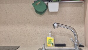 A kitchen with a stainless steel sink, a green dish towel, a soap dispenser, and a white container with utensils. - 27 l Myeongdong 5min l Airport bus l Cozy Room (Seoul)