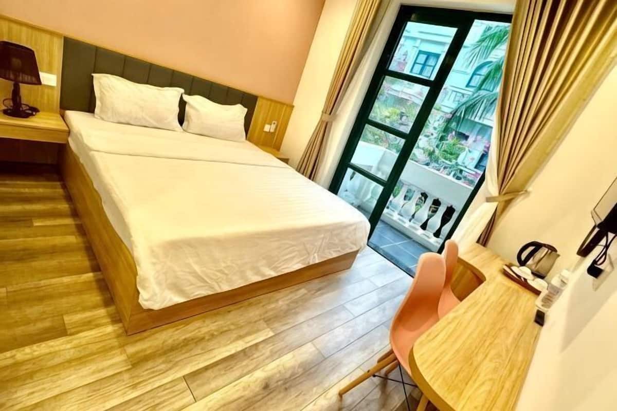 Camera d'albergo con un letto grande, una scrivania in legno e vista all'esterno.