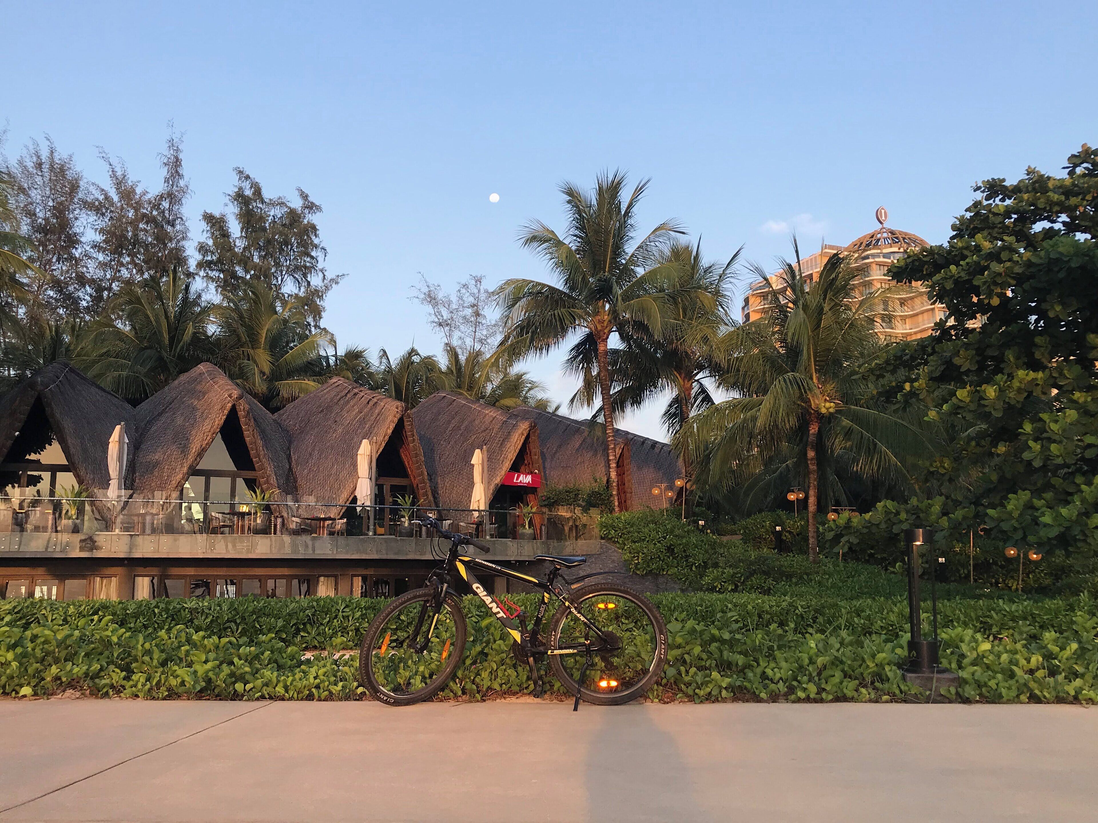 A bicycle parked in front of a building with thatched roofs and a sign reading "Lava".