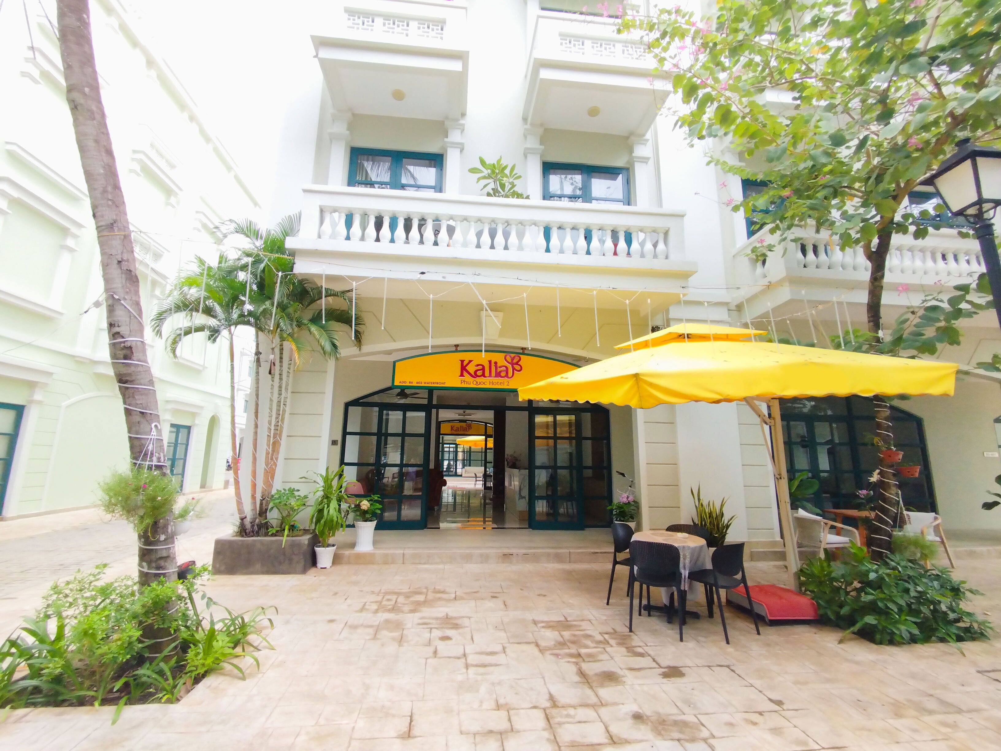A hotel entrance with a sign reading "Kalah", outdoor seating area, and potted plants.